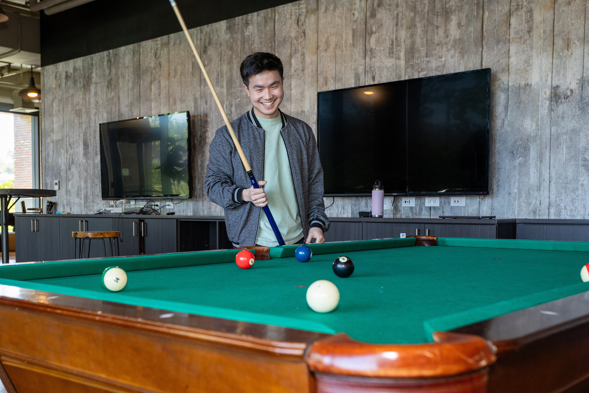 A person playing pool in the recreation space shown on HPR’s careers page