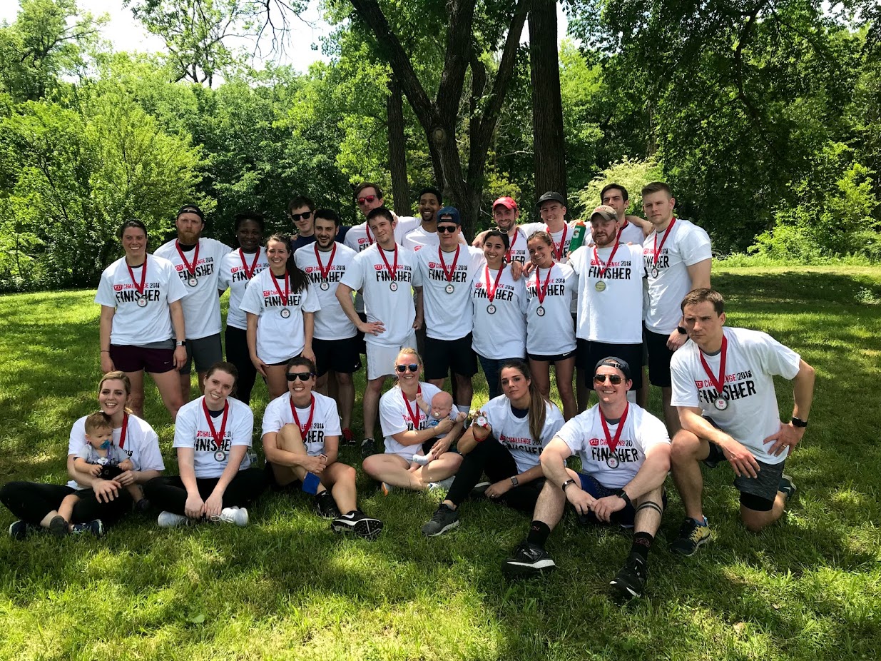 Call Box team members wearing finisher shirts and medals, gathered outdoors beneath trees