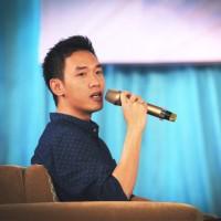Huy Dinh holding a microphone while seated