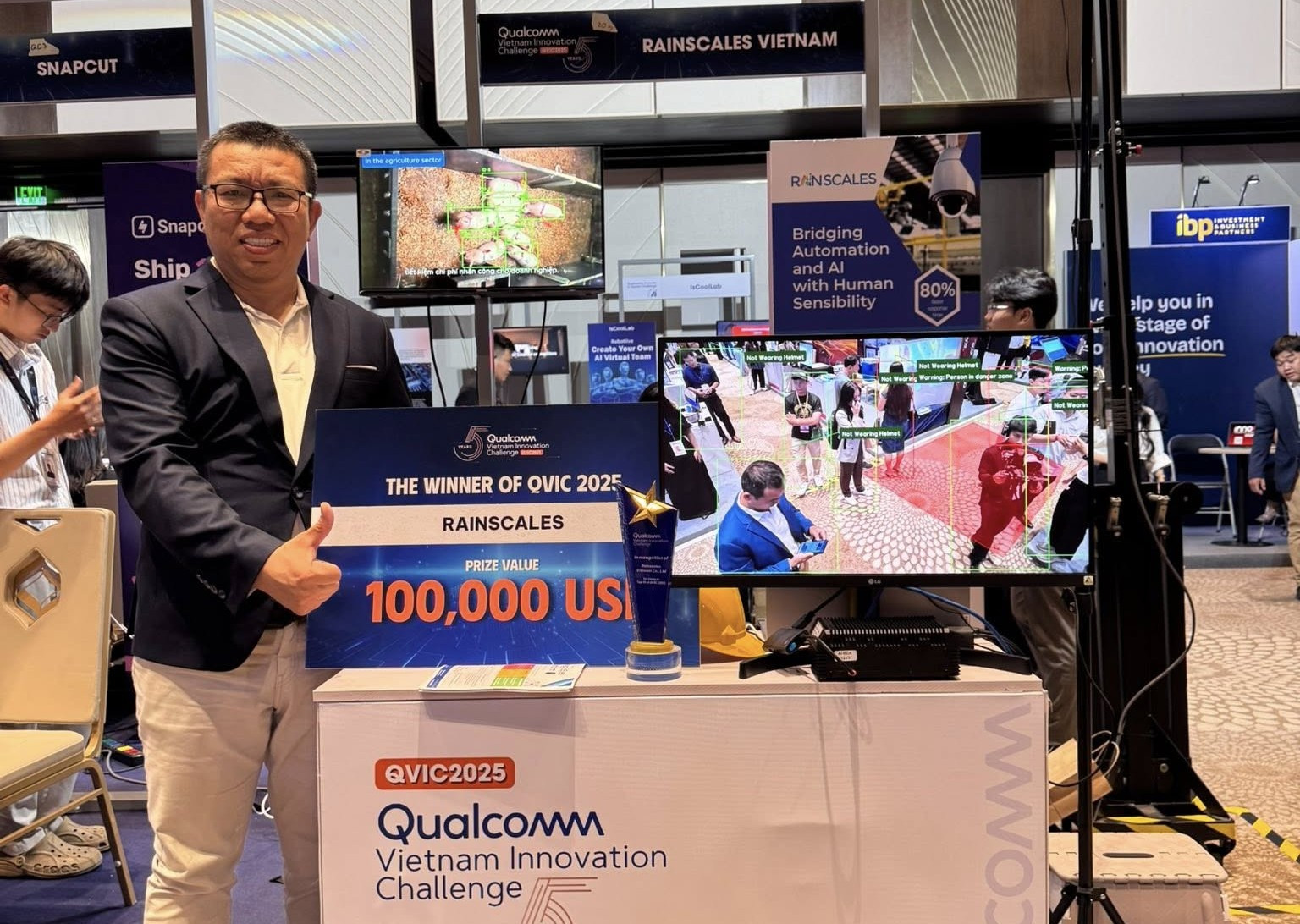 Huy Tran holding Rainscales’ QVIC 2025 first-prize award beside a computer vision demonstration at InnoEx