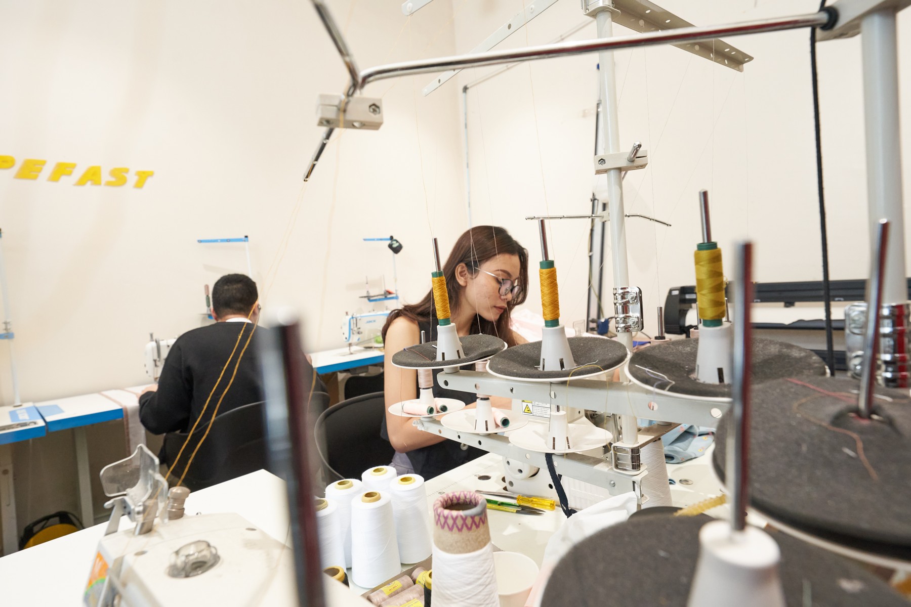 People working among sewing machines and thread spools in a Hypefast workshop