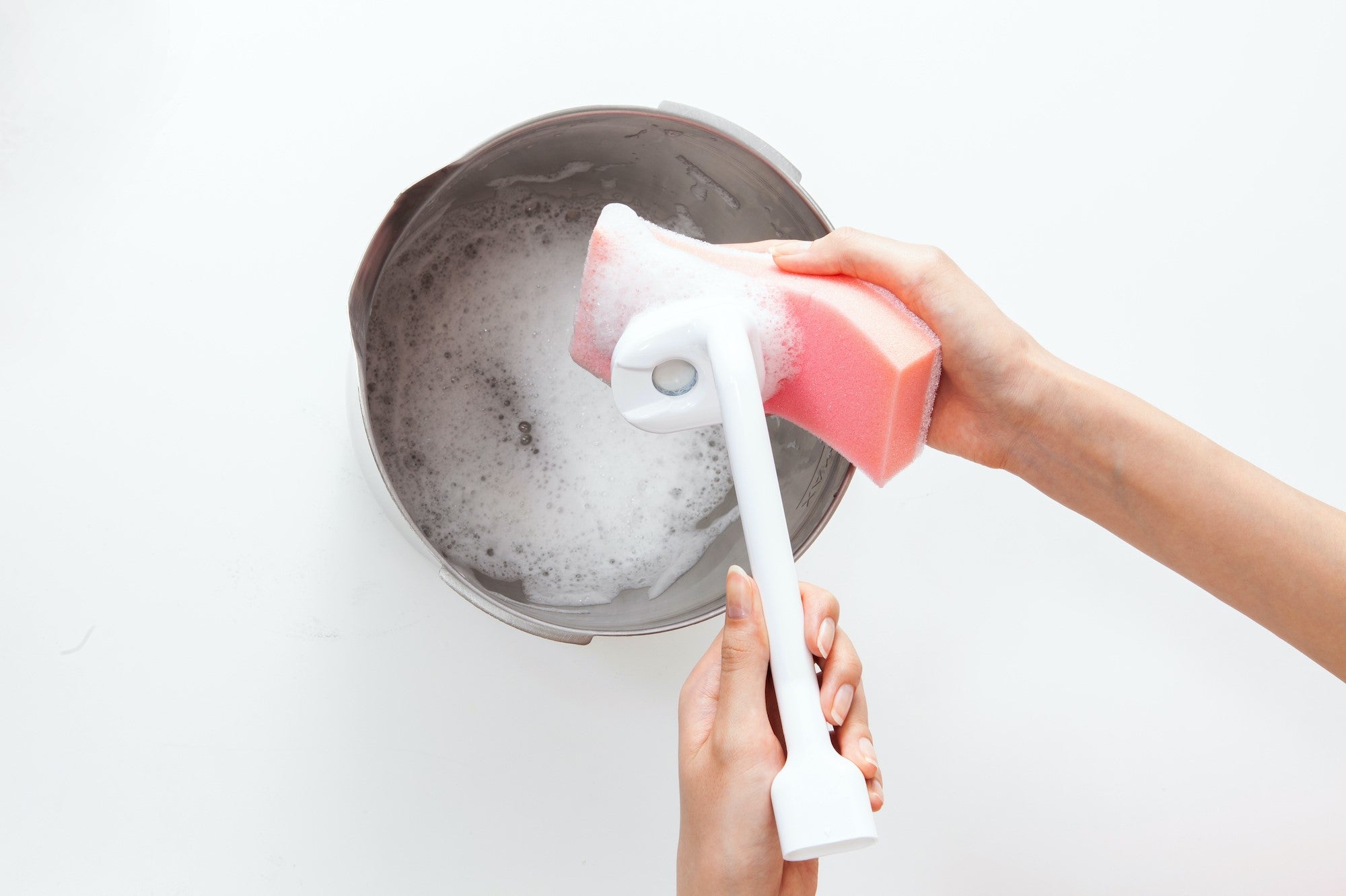 A sponge washing Carepod’s detachable oscillator beside a stainless-steel tank