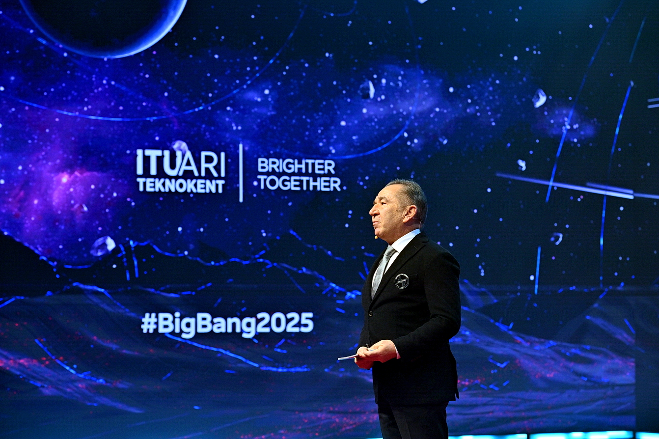 A speaker on the blue-lit Big Bang 2025 stage