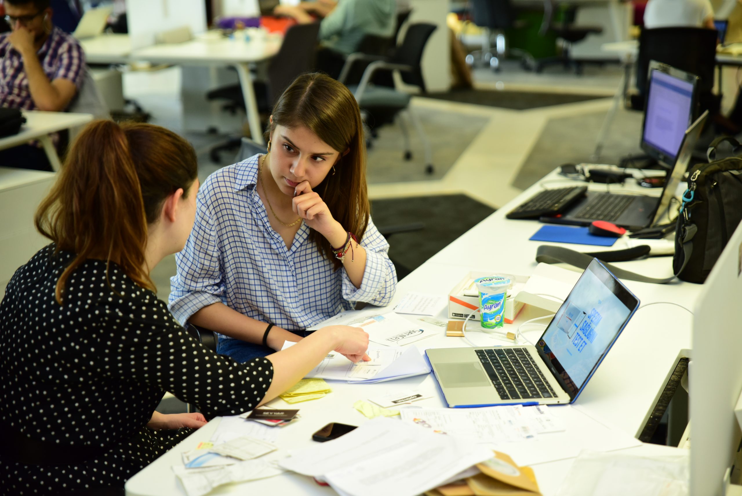 Two people discussing papers beside laptops in İTÜ Çekirdek’s shared workspace