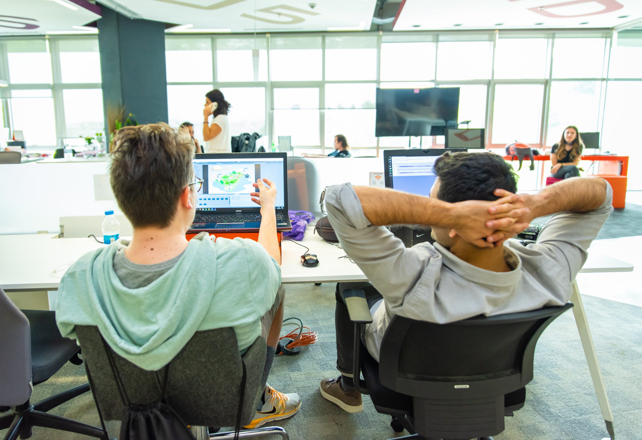 People reviewing a laptop screen together in the open workspace