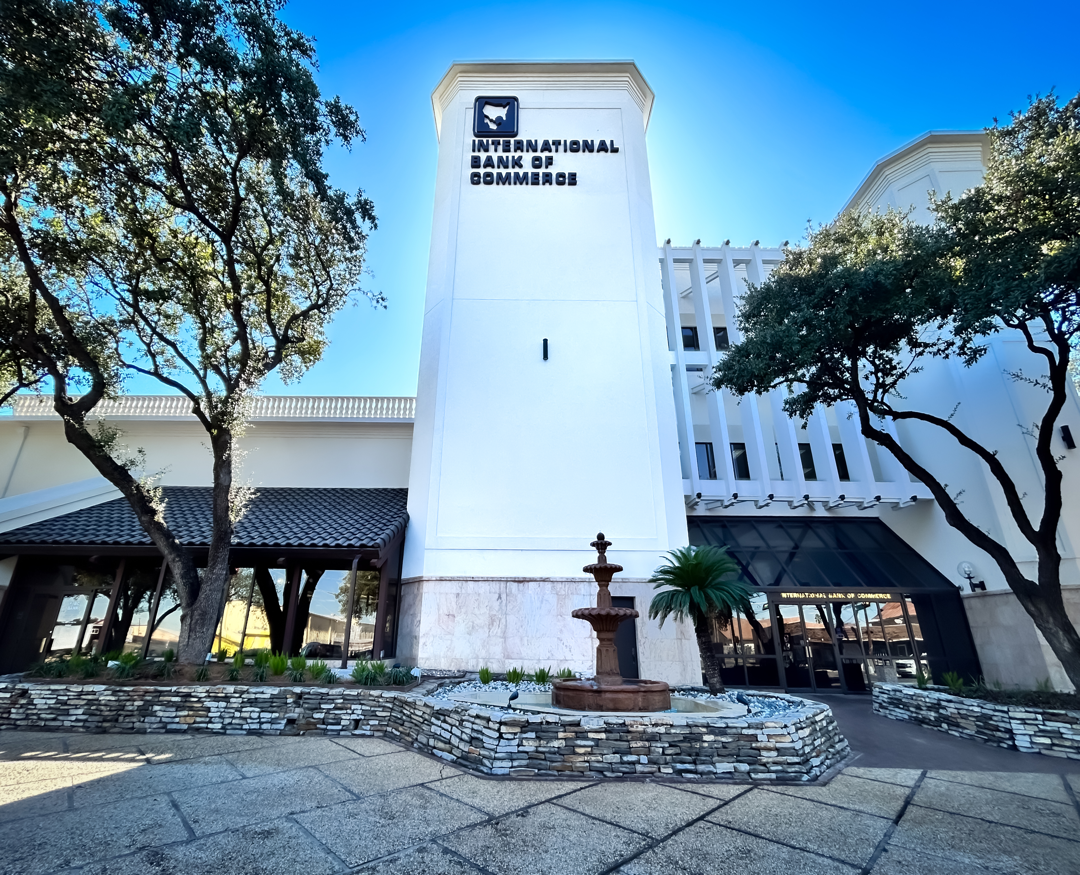 An International Bank of Commerce building framed by trees and a fountain