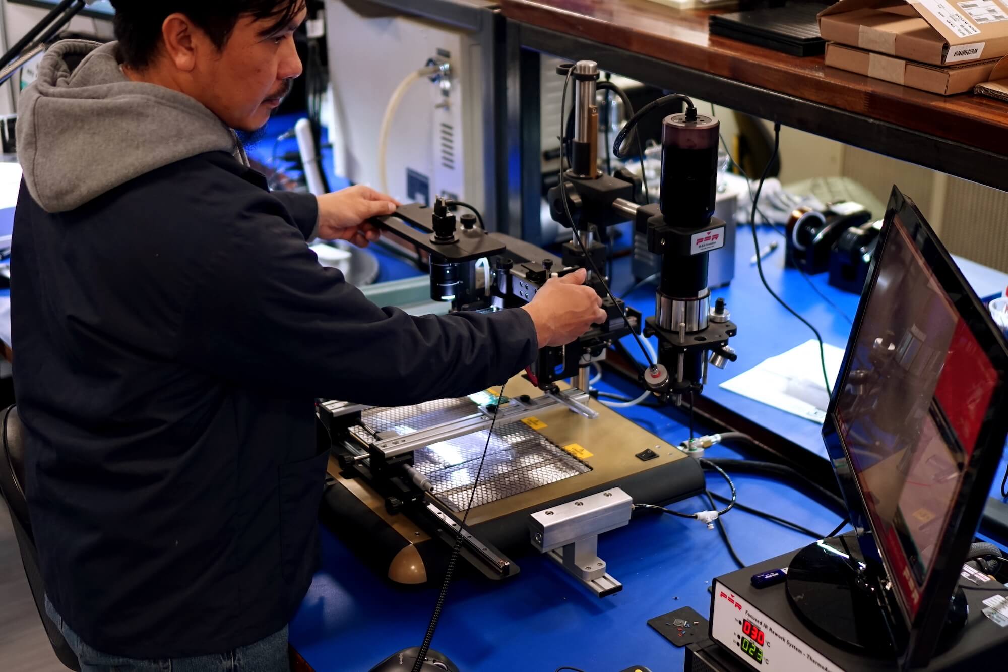An Ibeos technician working at electronics manufacturing equipment in the company's facility