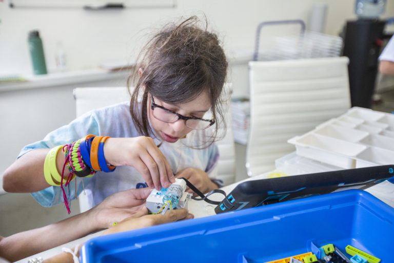 A child concentrates while assembling a small robotics project at iCAMP