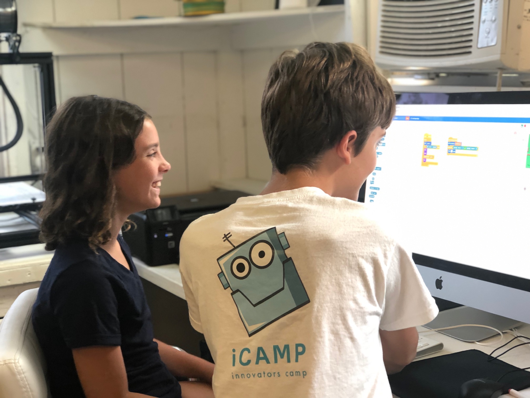 An iCAMP instructor helps a student work with Scratch programming on a desktop computer