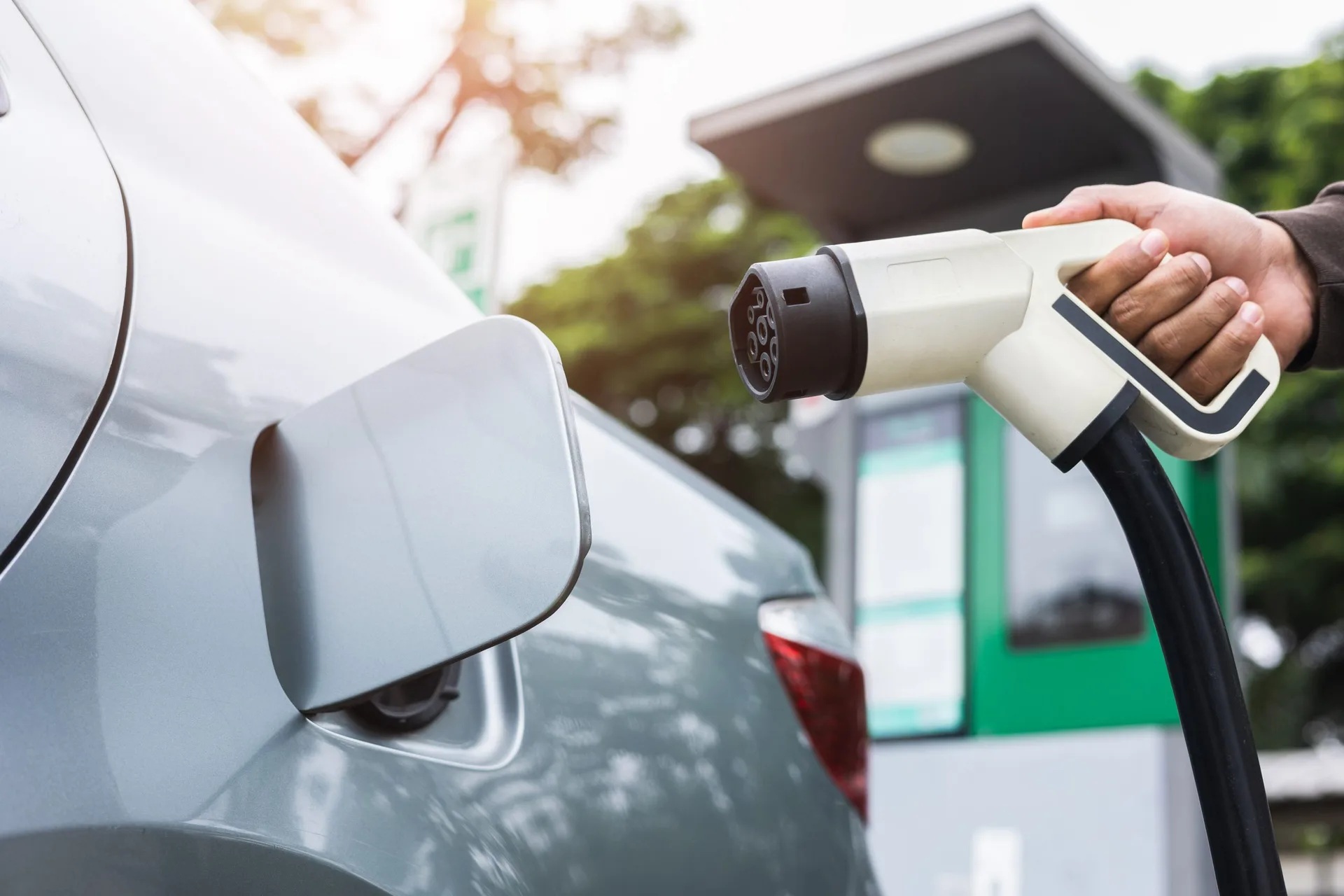 An electric vehicle charging connector being brought toward a car