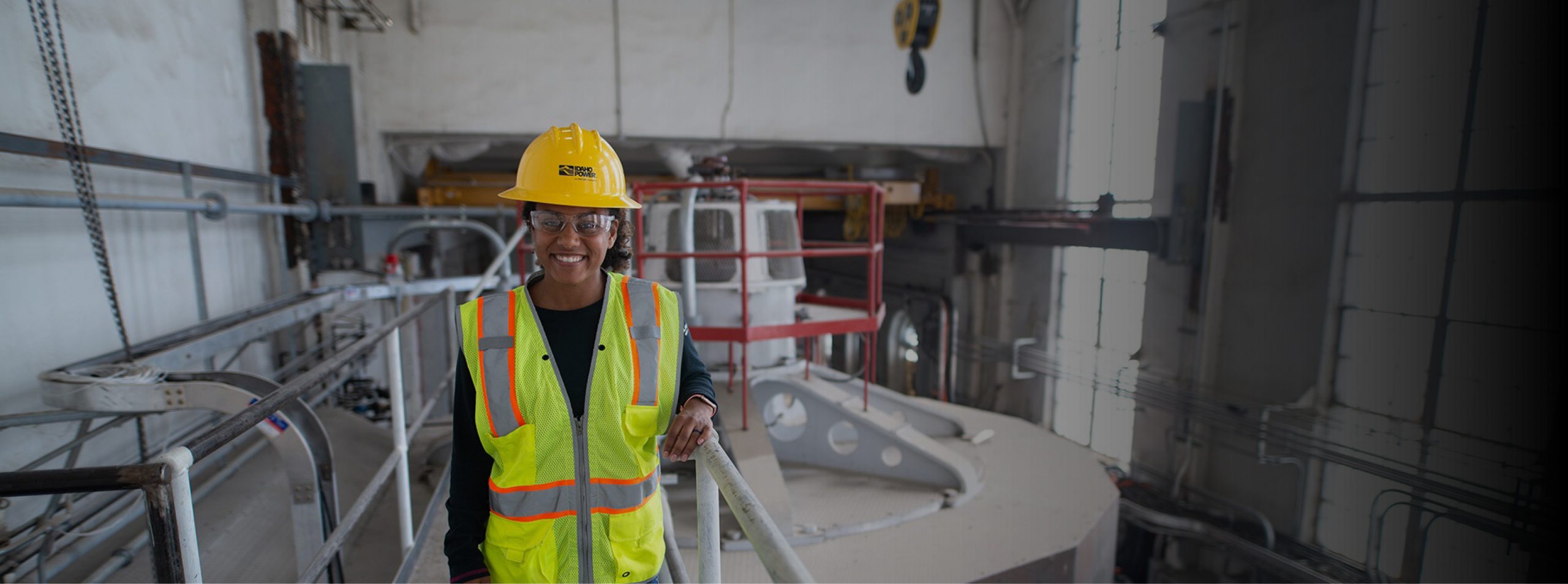 An Idaho Power engineer wearing a hard hat and safety vest inside a power plant