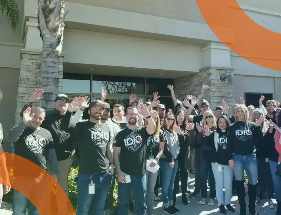 IDIQ employees wearing company T-shirts and waving outside the campus