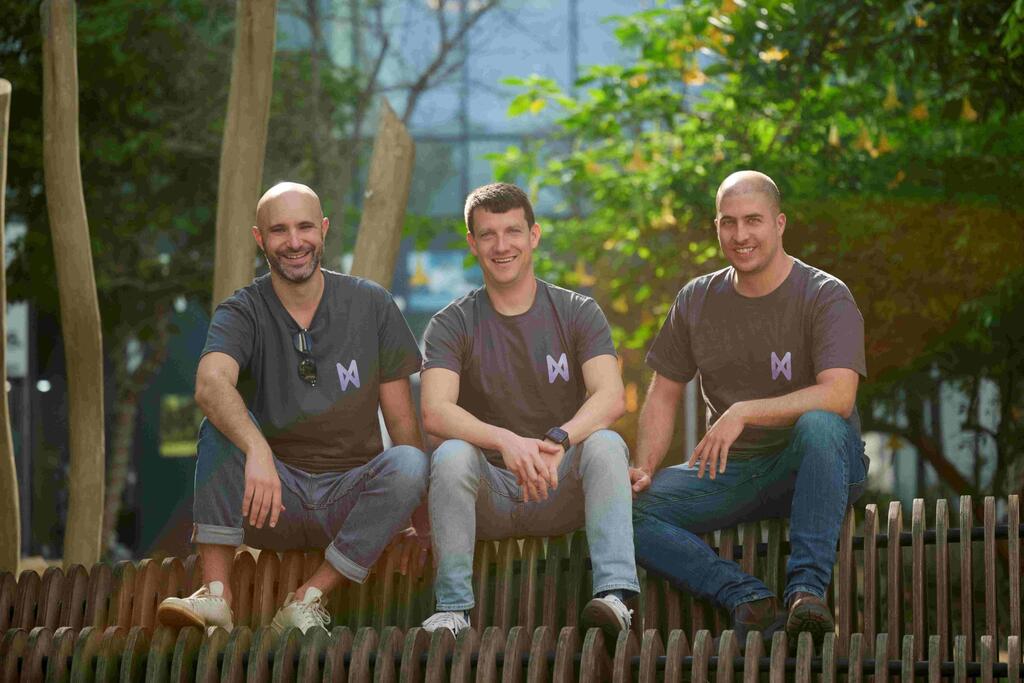 Novee’s three co-founders seated outdoors, with Ido Geffen in the center
