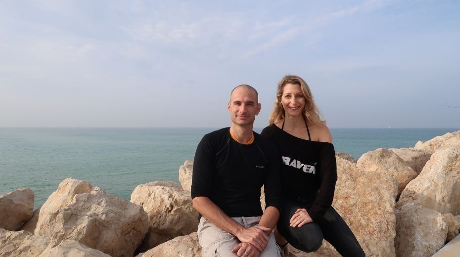 Ido Sella and Shimrit Perkol-Finkel seated together on coastal rocks beside the sea