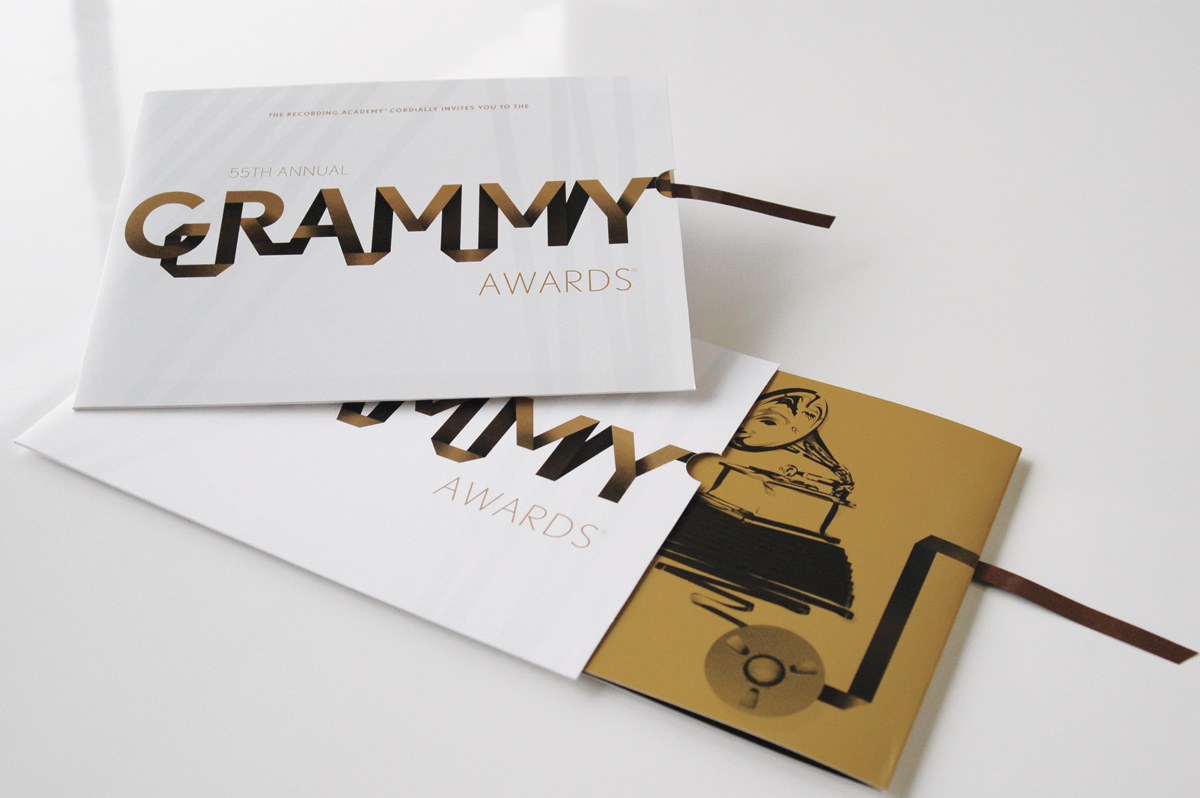 White and gold Grammy invitations with recording tape extending from the sleeves