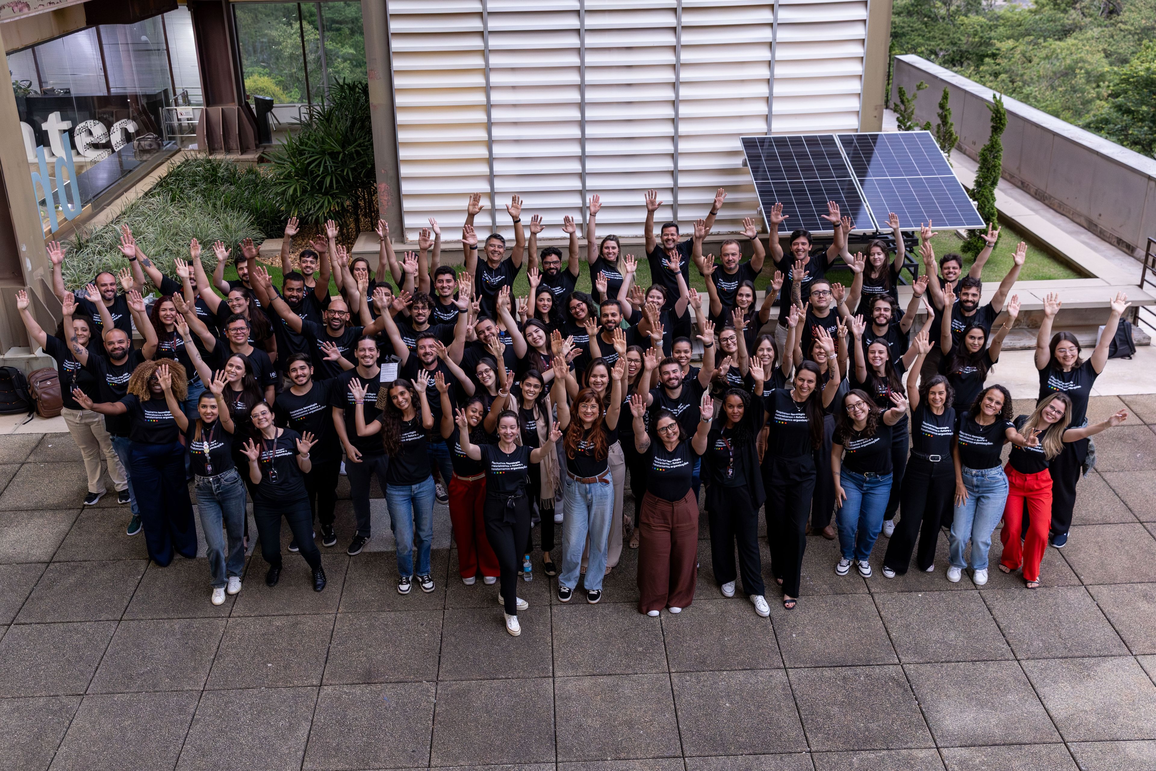 IEBT colleagues gathered outdoors, smiling and raising their hands