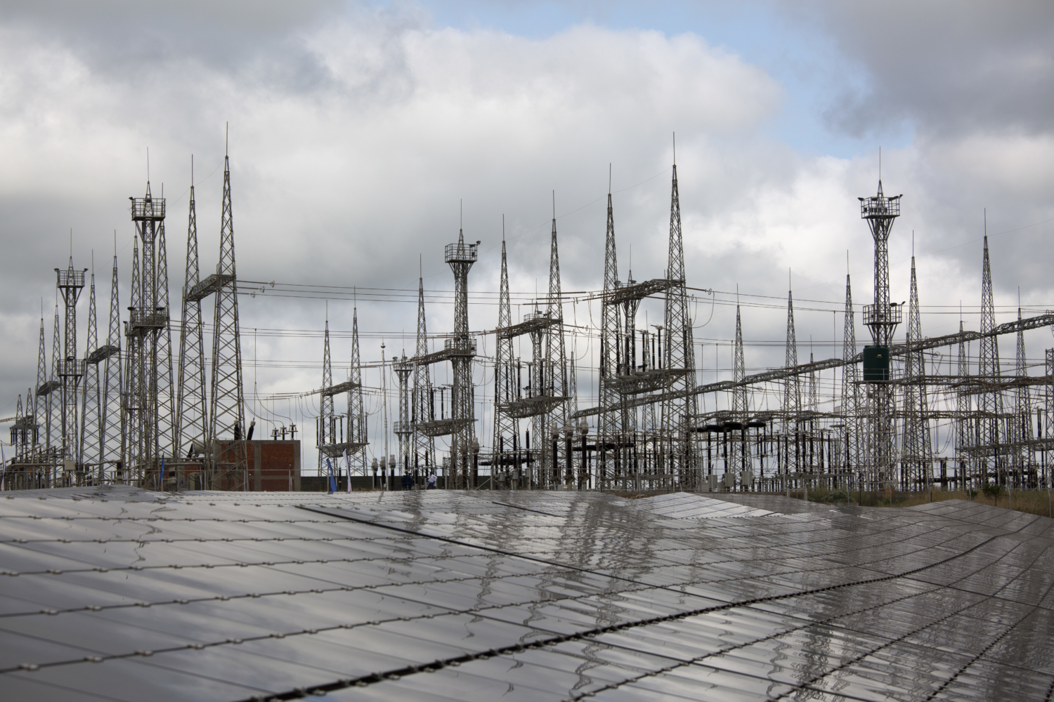 Solar panels in front of electricity infrastructure at the Zambia project