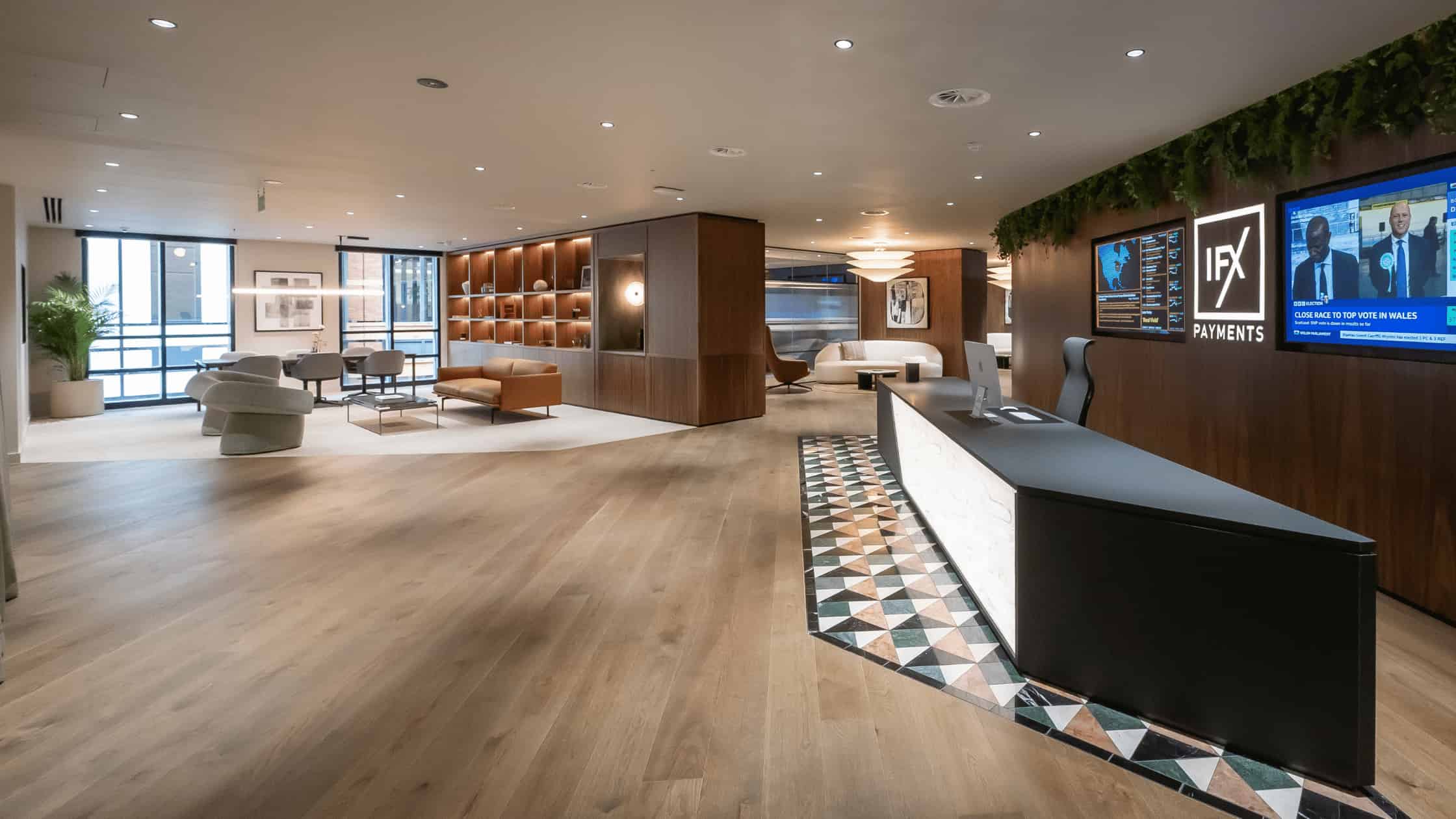 IFX Payments office reception with seating, screens and a curved reception desk