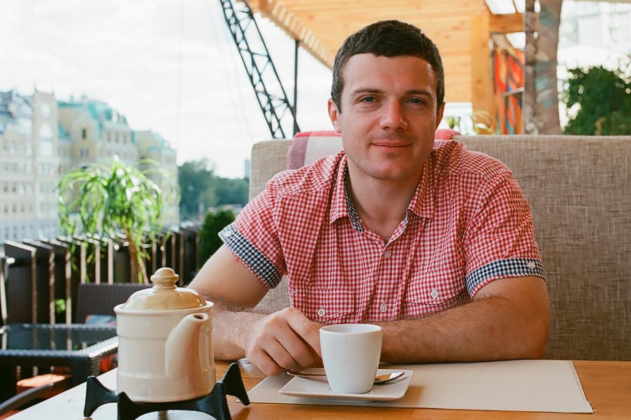 Igor Arkhipov seated at a cafe table with a cup and teapot