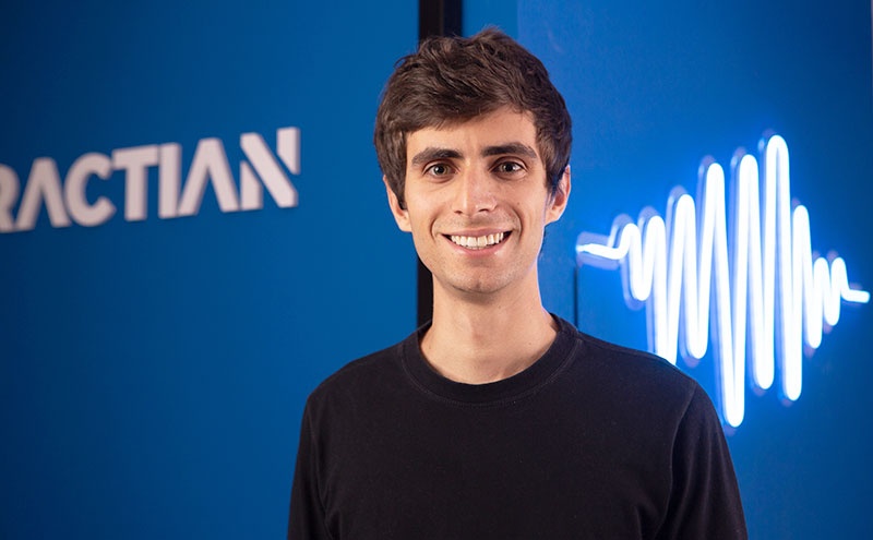 Igor Marinelli in front of Tractian’s blue wall and waveform graphic