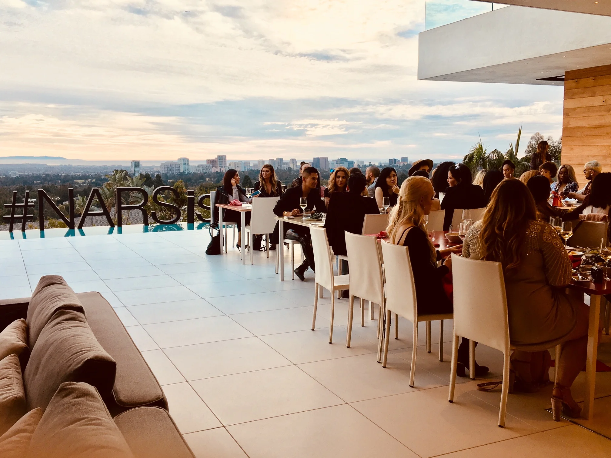 Guests at a NARS Friendsgiving dinner on a terrace overlooking Los Angeles