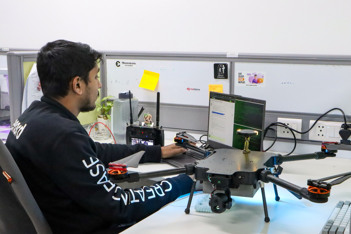 A person working at a laptop with a large drone spread across an incubator workstation