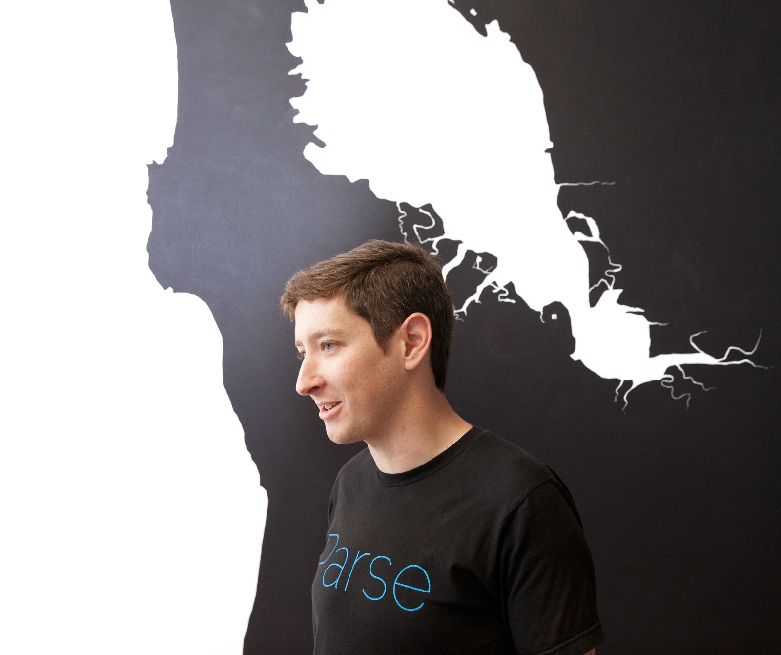 Ilya Sukhar in a black Parse T-shirt in front of a wall map