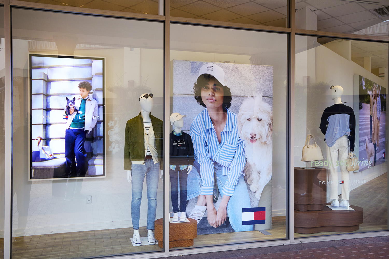 Tommy Hilfiger spring window display with mannequins, large photographs, and wood-look plinths