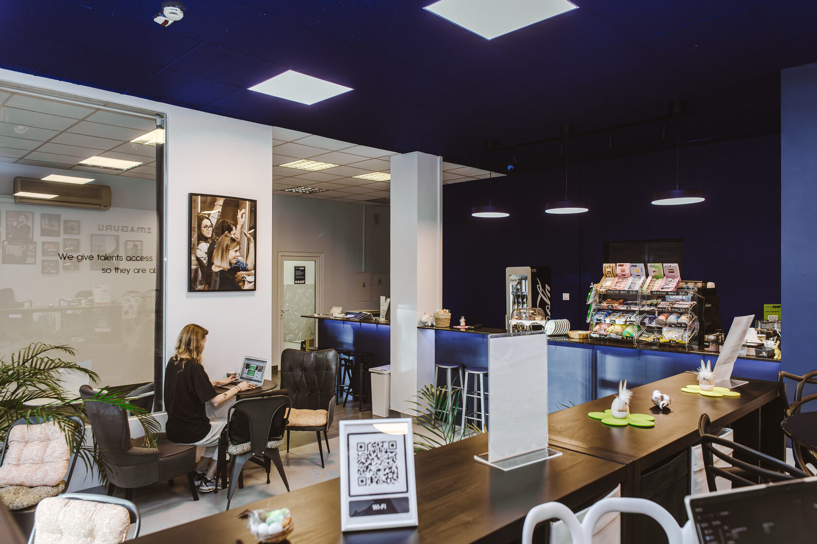 Imaguru Warsaw workspace with cafe counter, shared tables, seating and a person working on a laptop