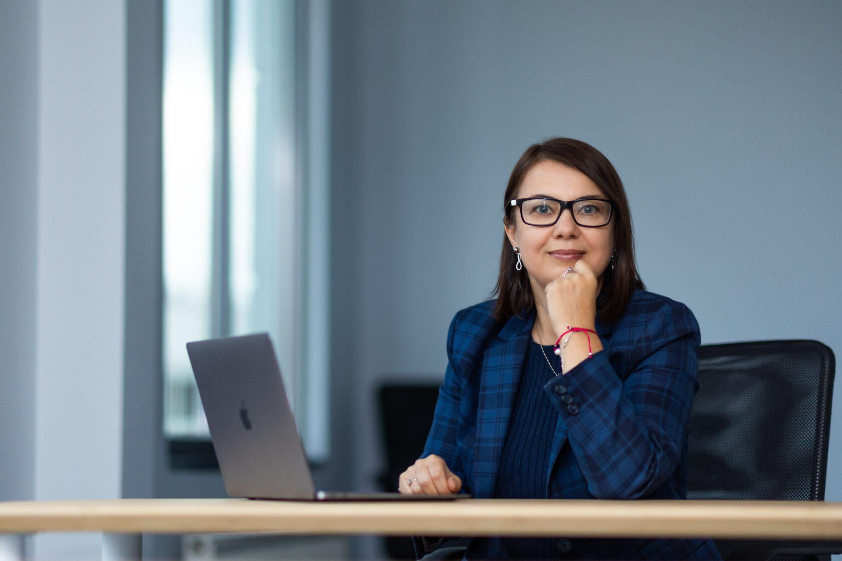 Portrait published by Imaguru in its leadership section, showing a woman seated at a desk beside a laptop
