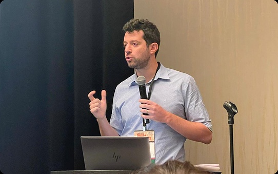 Impala co-founder Shahar Brukner speaking with a microphone beside a laptop