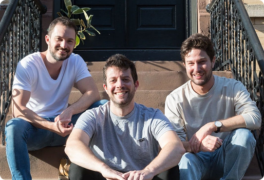 Three members of the Impala team sitting together on outdoor steps in a company gallery photograph