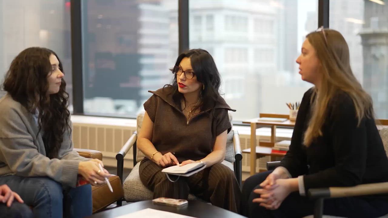 Three Imre team members in conversation around a table in a bright office