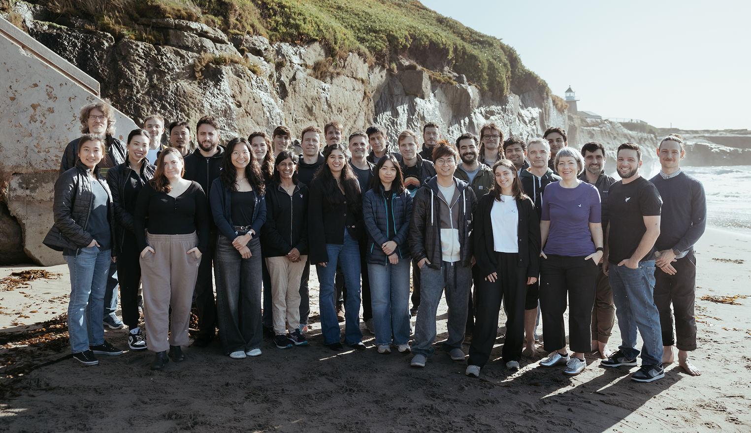 Inceptive team gathered on a beach near a rocky shoreline
