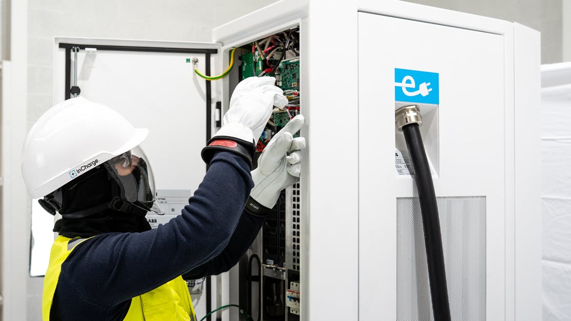 A technician in protective equipment working inside an InCharge charger cabinet