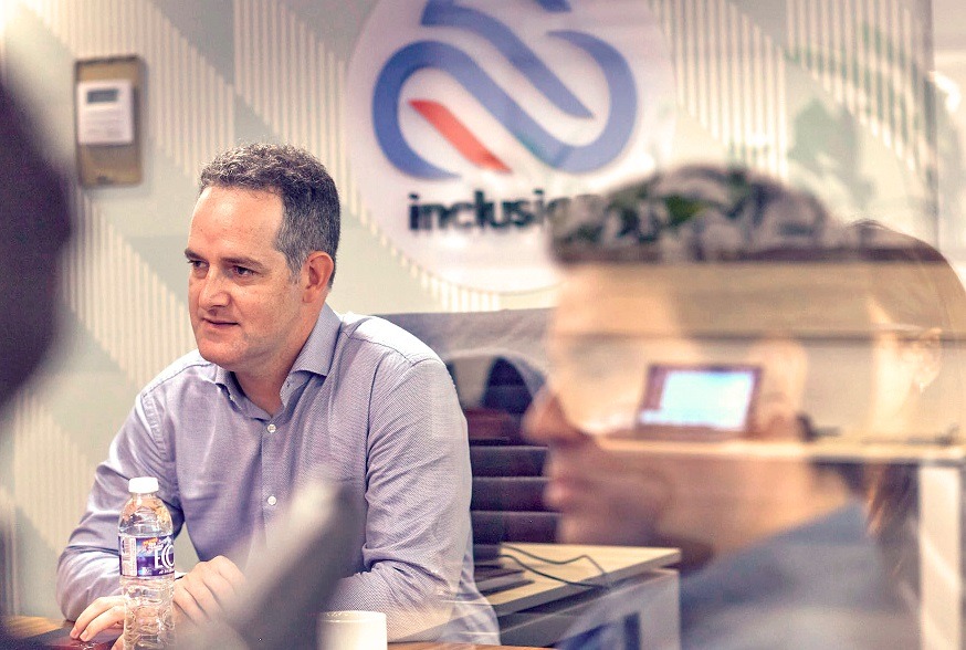 Inclusion Cloud founder Mariano Baca-Storni seated in a meeting, photographed through glass