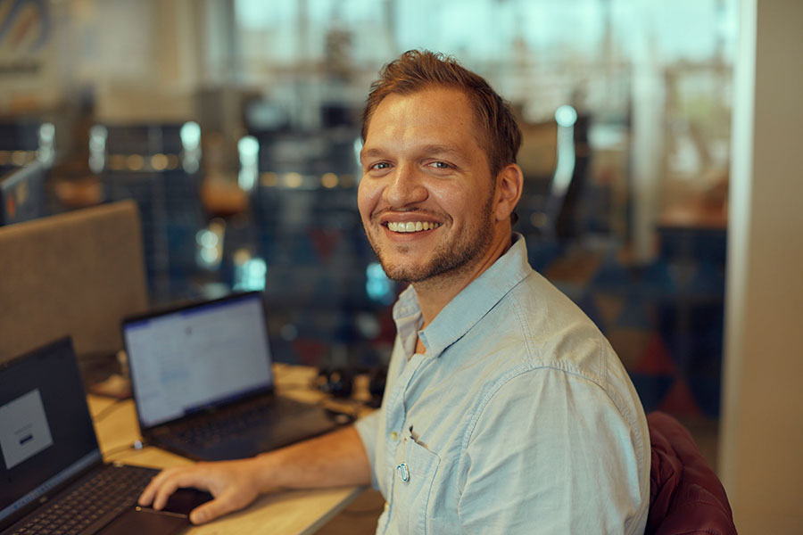 A consultant pictured at a desk with laptops, from Inclusion Cloud’s engineering team page