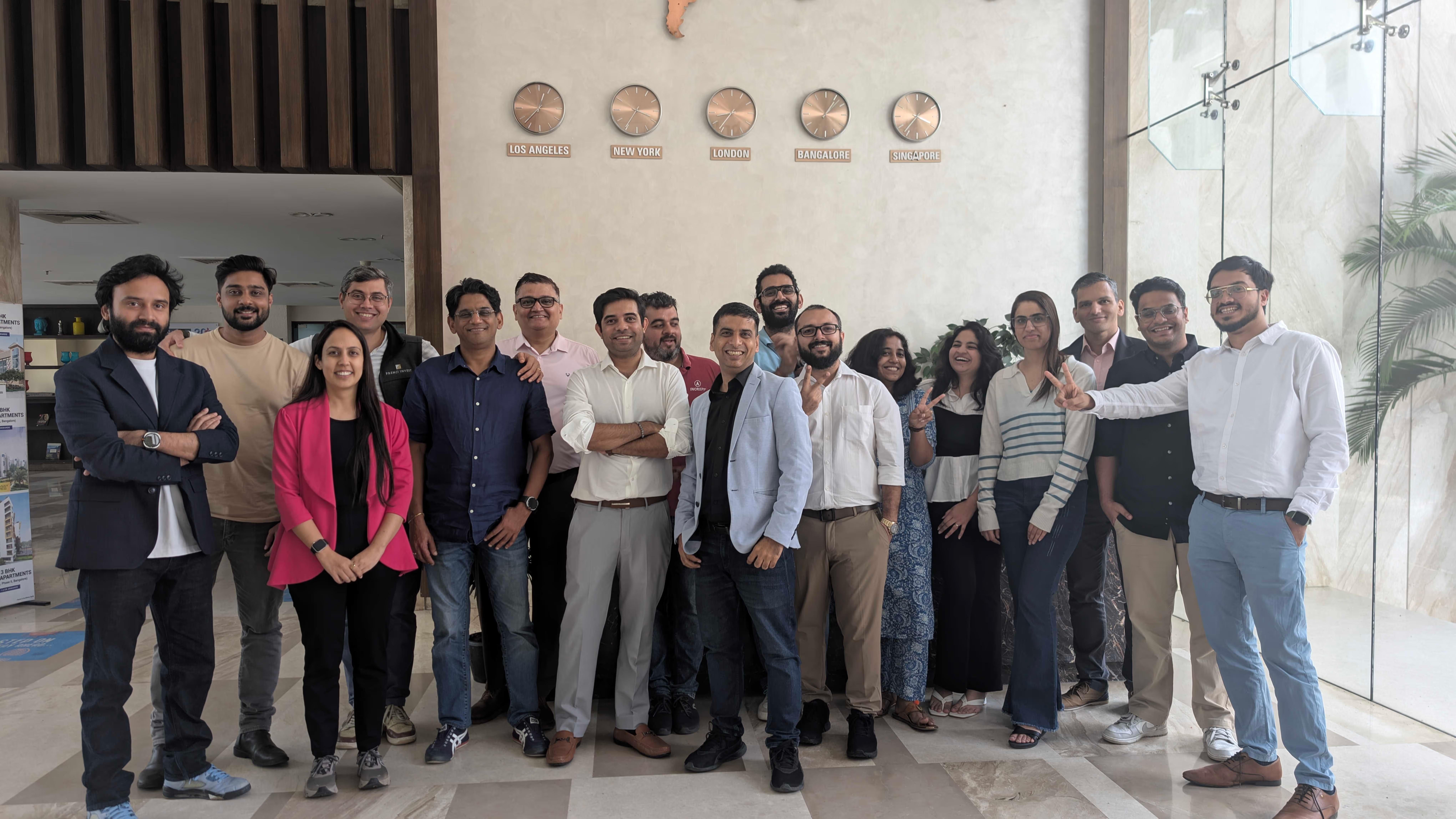 Increff team gathered beneath clocks labeled Los Angeles, New York, London, Bangalore, and Singapore
