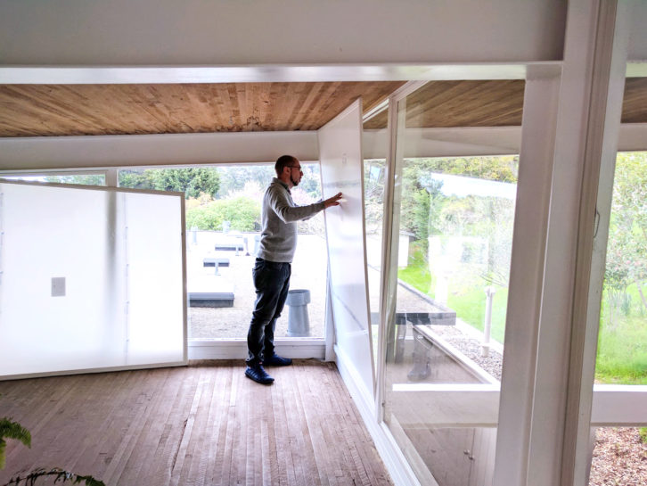 A person installing a large clear Indow insert inside a modern window wall