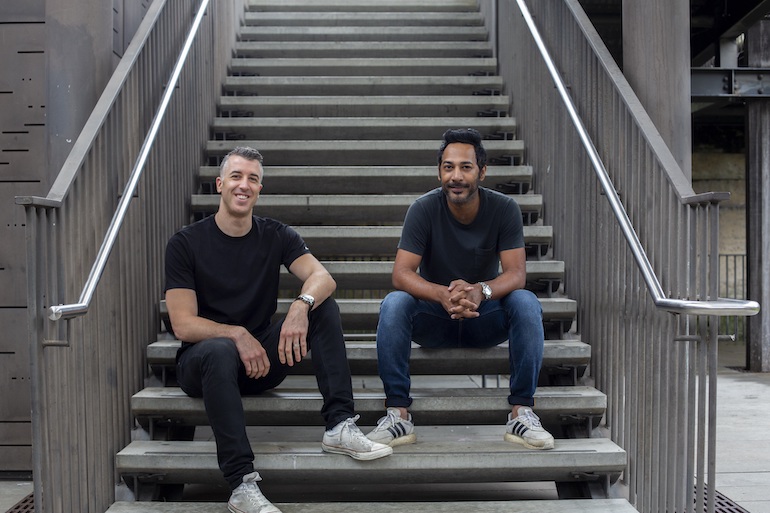 Brad Manuel and Indy Khabra sitting side by side on an outdoor staircase