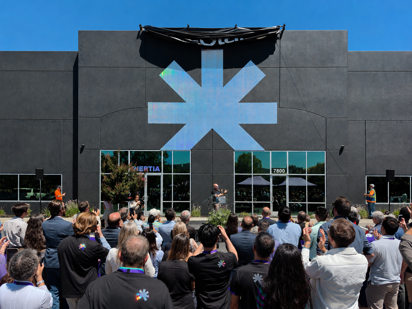 Crowd gathered outside Inertia's Livermore headquarters beneath a large star-shaped company symbol