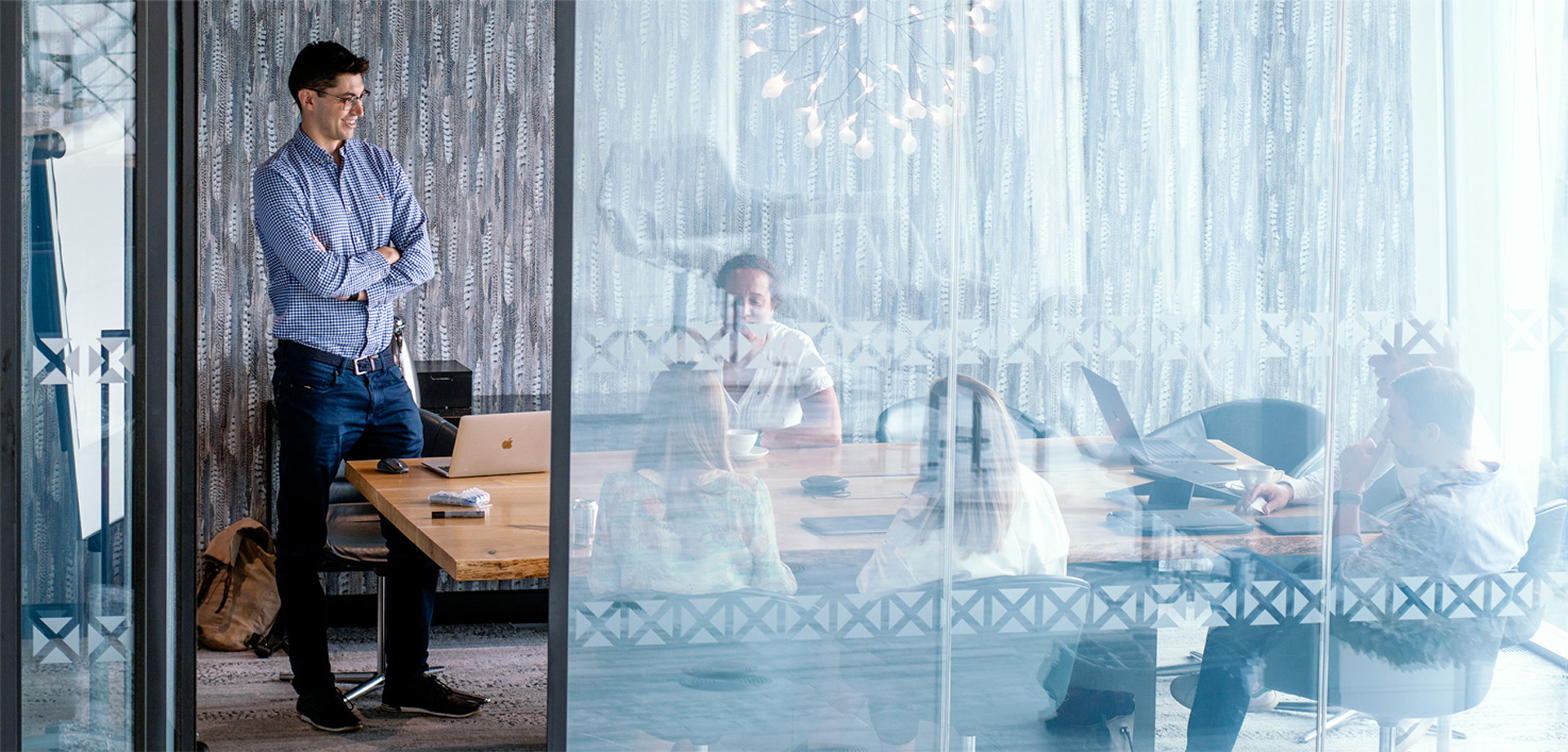 Colleagues gathered around laptops in a glass-walled meeting room, from Infinite Lambda’s careers photography