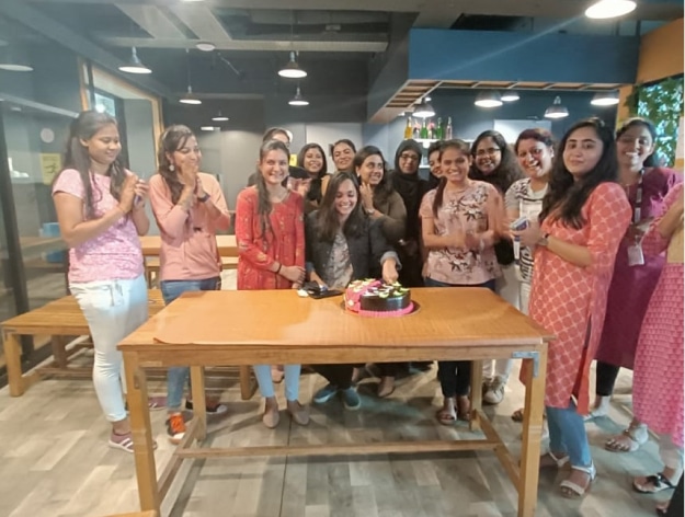 Colleagues gathered around a cake during an office celebration in InfoAnalytica’s careers gallery