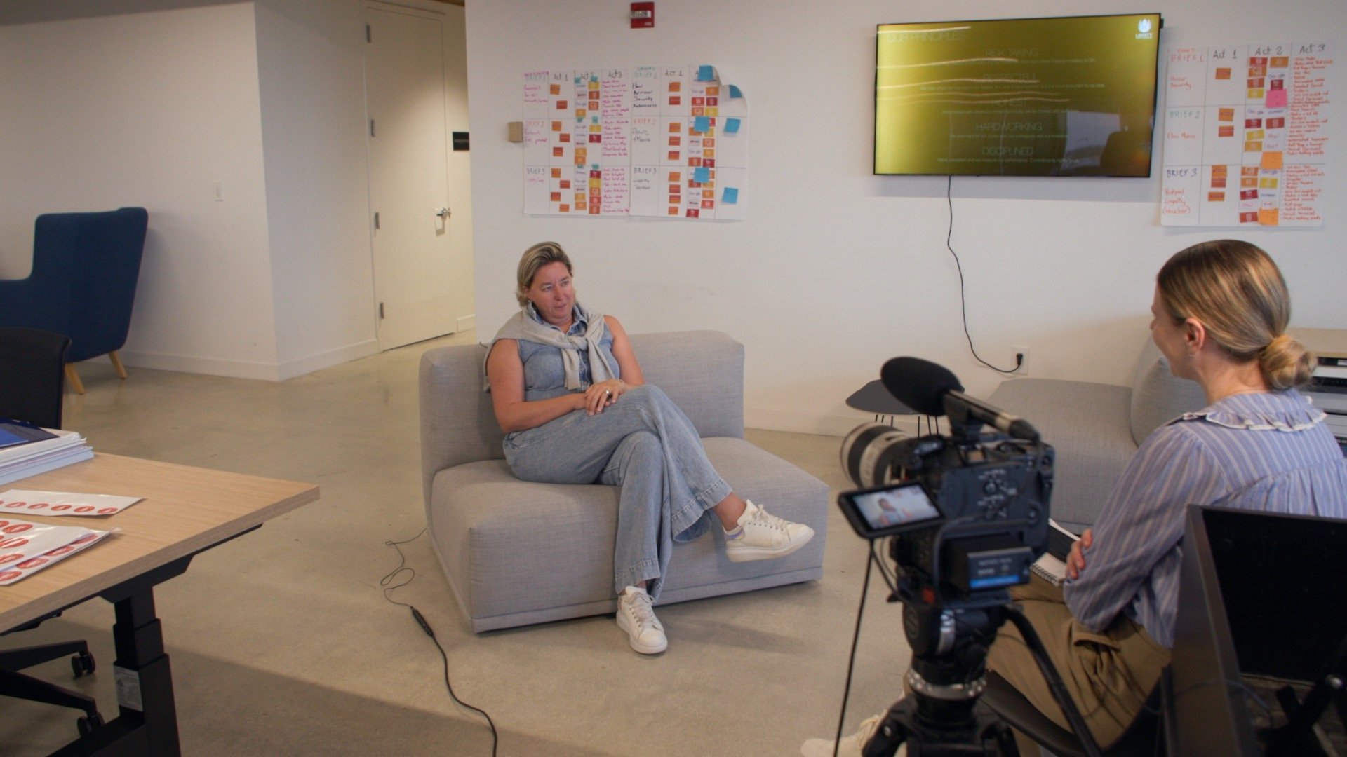 Inge Smidts seated opposite interviewer Tamara Moellenberg during a filmed conversation at an office