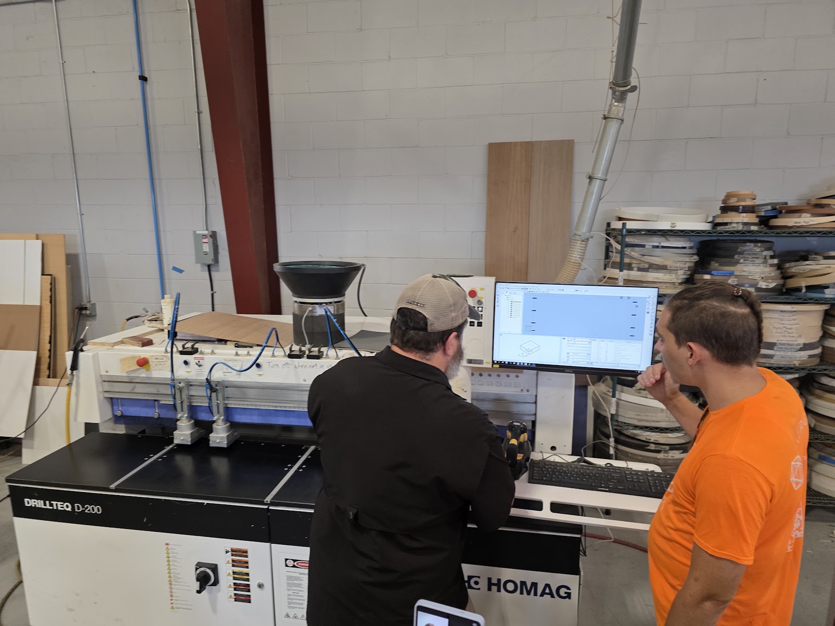 Two people reviewing INNERGY Engineering beside a woodworking machine