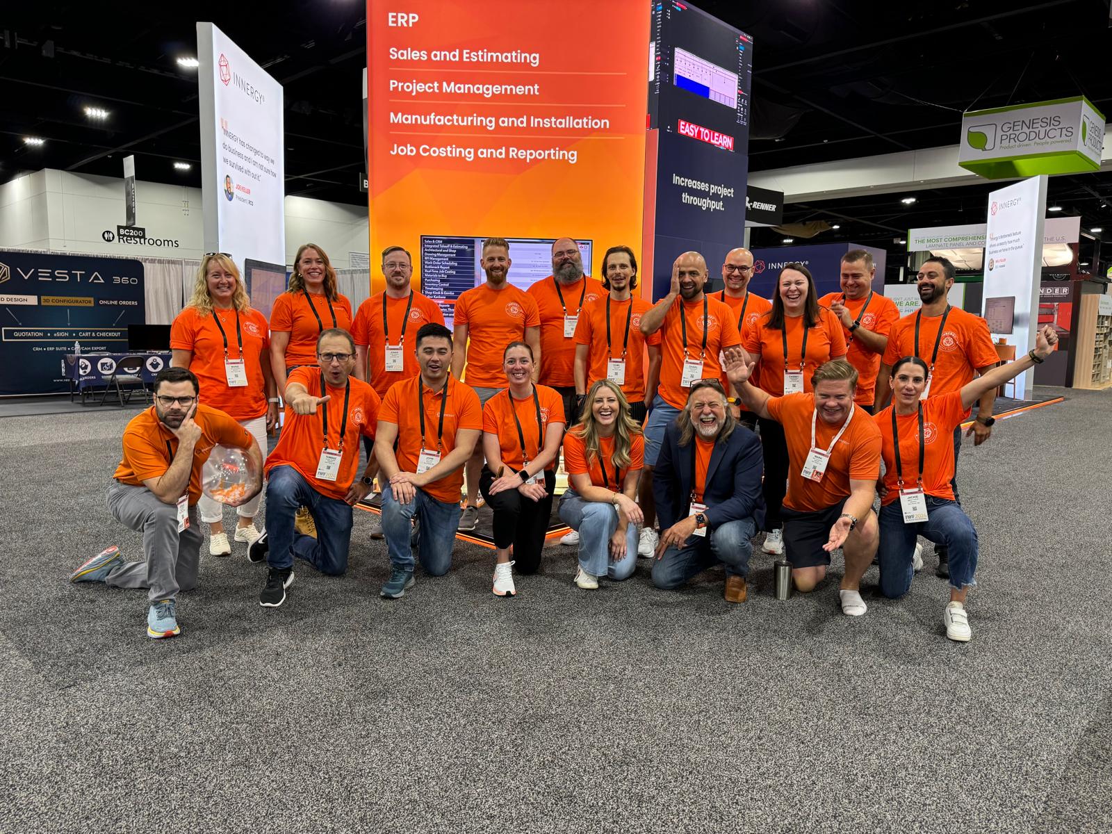 The INNERGY team in orange shirts at a woodworking trade show