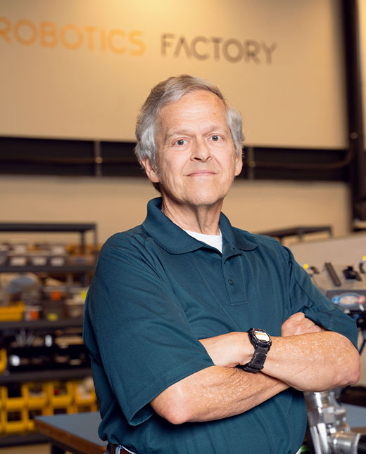 A Robotics Factory program portrait with workbenches in the background