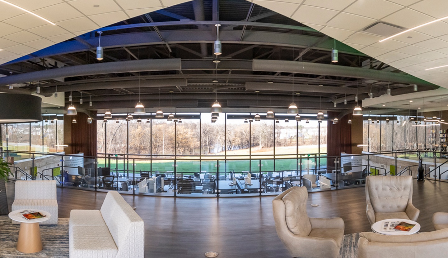 Open corporate office with glass railings, lounge seating, and large windows