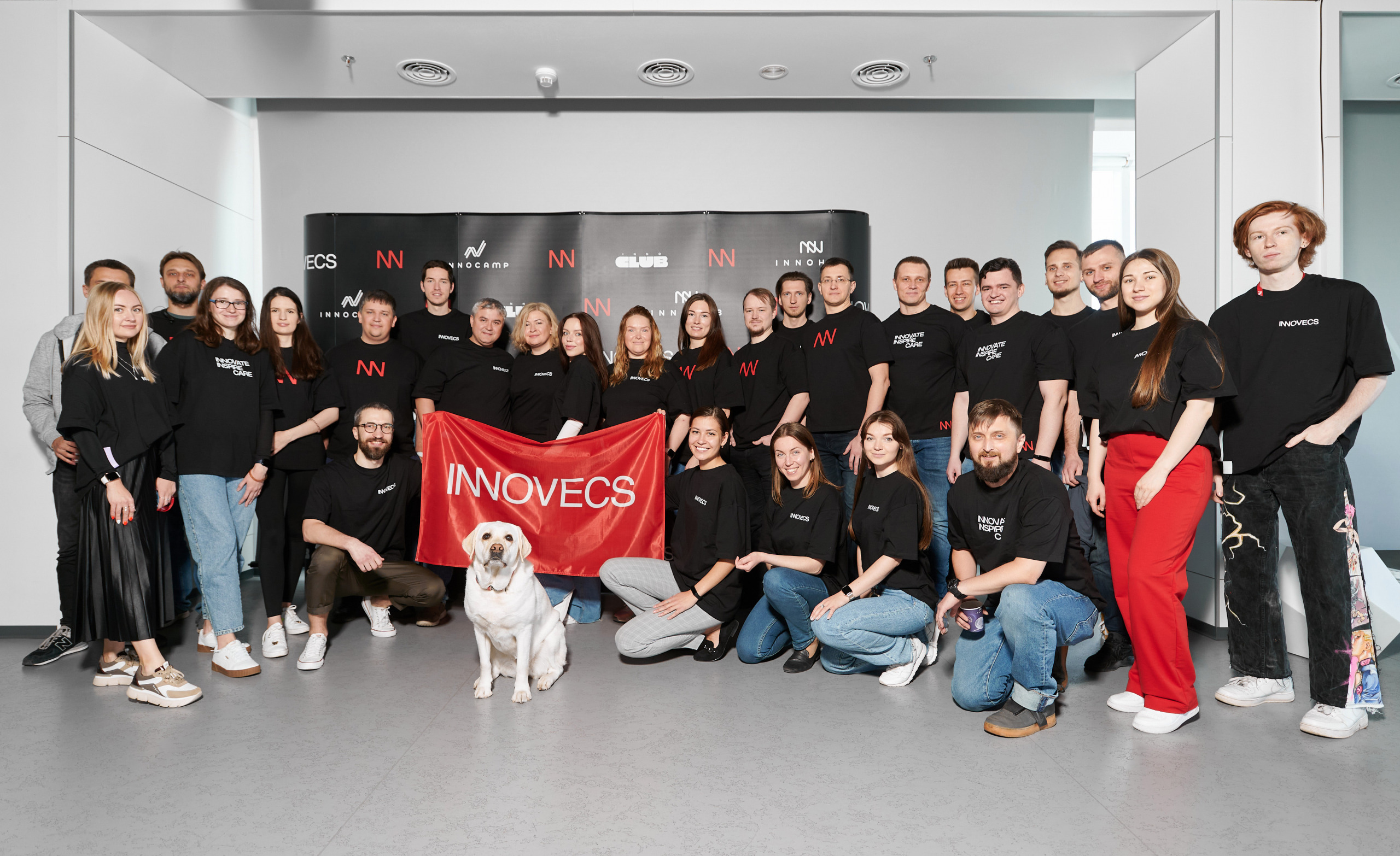 Innovecs team posing together with a Labrador in the foreground