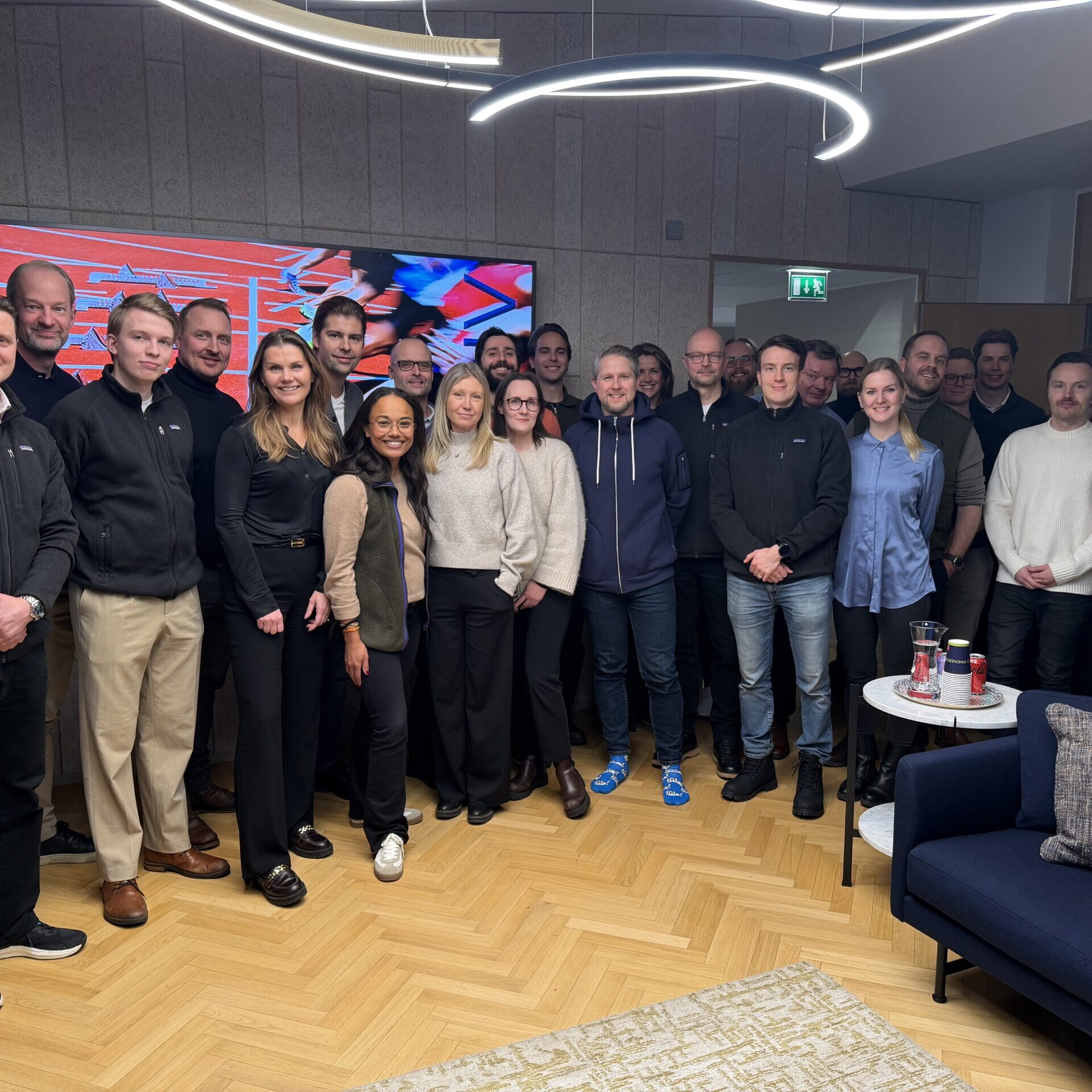 Innovestor colleagues gathered indoors beneath circular ceiling lights
